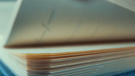 a macro close up shot of fast rolling pages of a blank notebook, cinematic studio lighting, 120 fps, slow motion, full hd