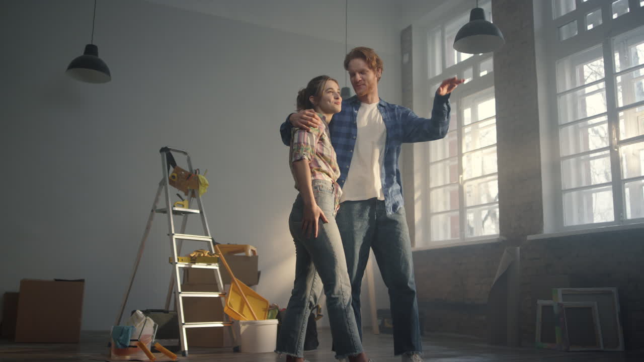 Blije familie knuffelt in nieuw appartement. Vrolijk stel bespreekt huisrenovatie.