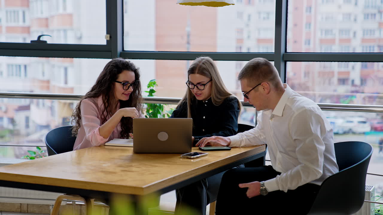 Colleagues communicating and cooperating in the office. Young people using technologies and gadgets in their work.