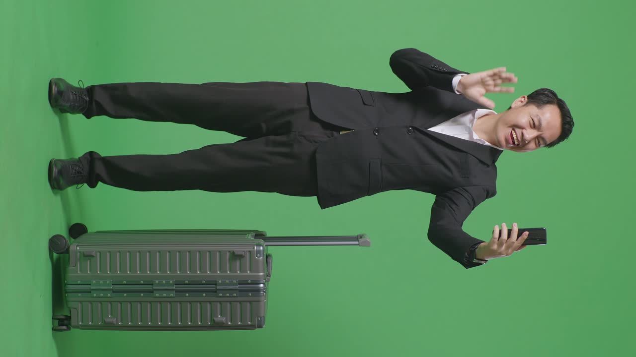 비즈니스맨이 초록색 스크린 앞에 수을 들고 셀피를 찍고 있다.