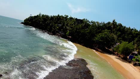 Aerial-Drone-Over-Popular-Sandy-Beach-With-Tourists-At-Beachfront-Hotels-On-Palm-Tree-Hillside-In-Sri-Lanka