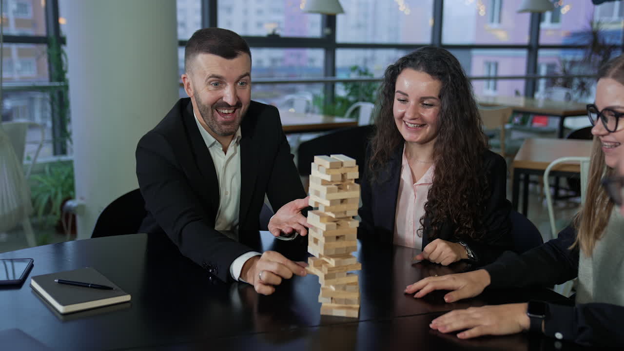Happy young people having fun playing table games. Business company playing jenga.