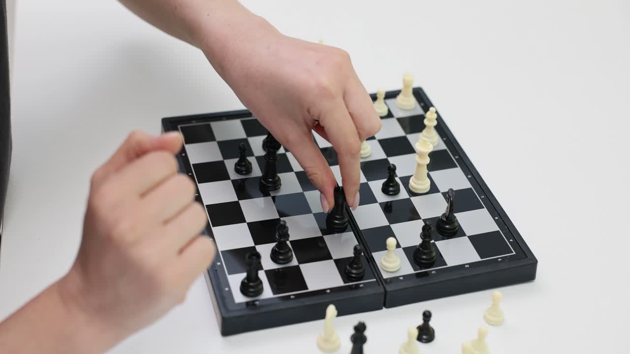 A person playing chess and moving a black pawn