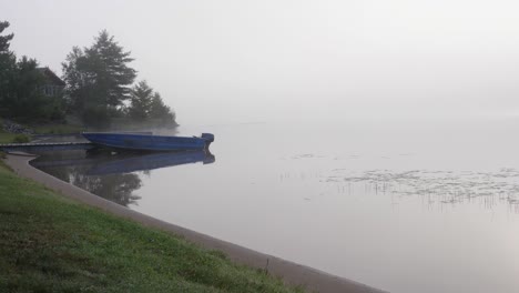 barco de aluminio de 14 pies atracado en una misteriosa mañana brumosa - lago brumoso ontario, canadá