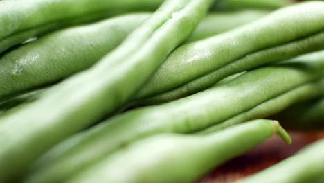 raw fresh uncooked string beans on wooden kitchen surface close up selective focus