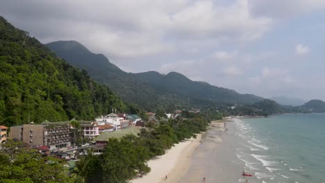 Vista-Aérea-A-Lo-Largo-De-La-Playa-De-Arena-Blanca-En-Koh-Chang-Con-Montañas-Boscosas-En-Segundo-Plano.