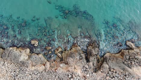 Beautiful-aerial-view-of-cliff-with-the-sea,-a-clear-blue-and-turquoise-sea-with-crystal-clear-and-calm-waters-lets-see-the-rocks-in-the-background