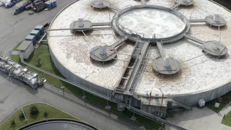 Aerial circling shot of large circular water treatment tank with aeration process at factory complex, Veille-Saint-Girons, France