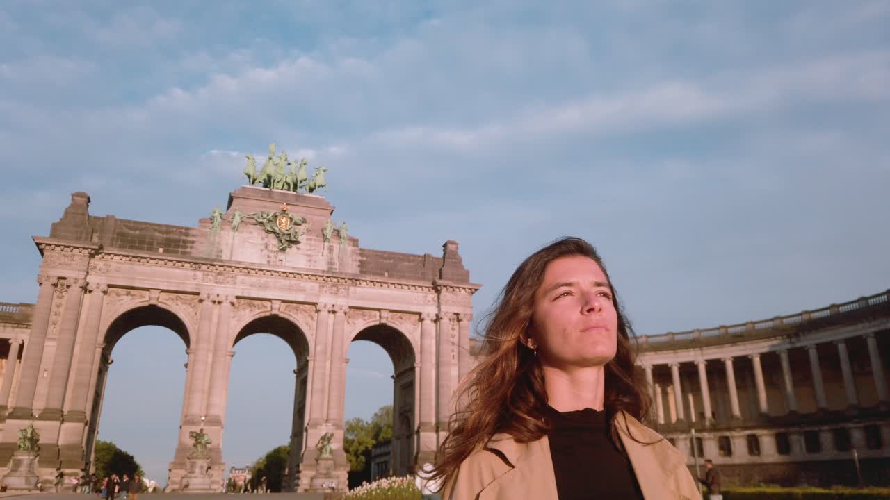 Woman walks past Cinquantenaire Arch in Brussels at sunset
