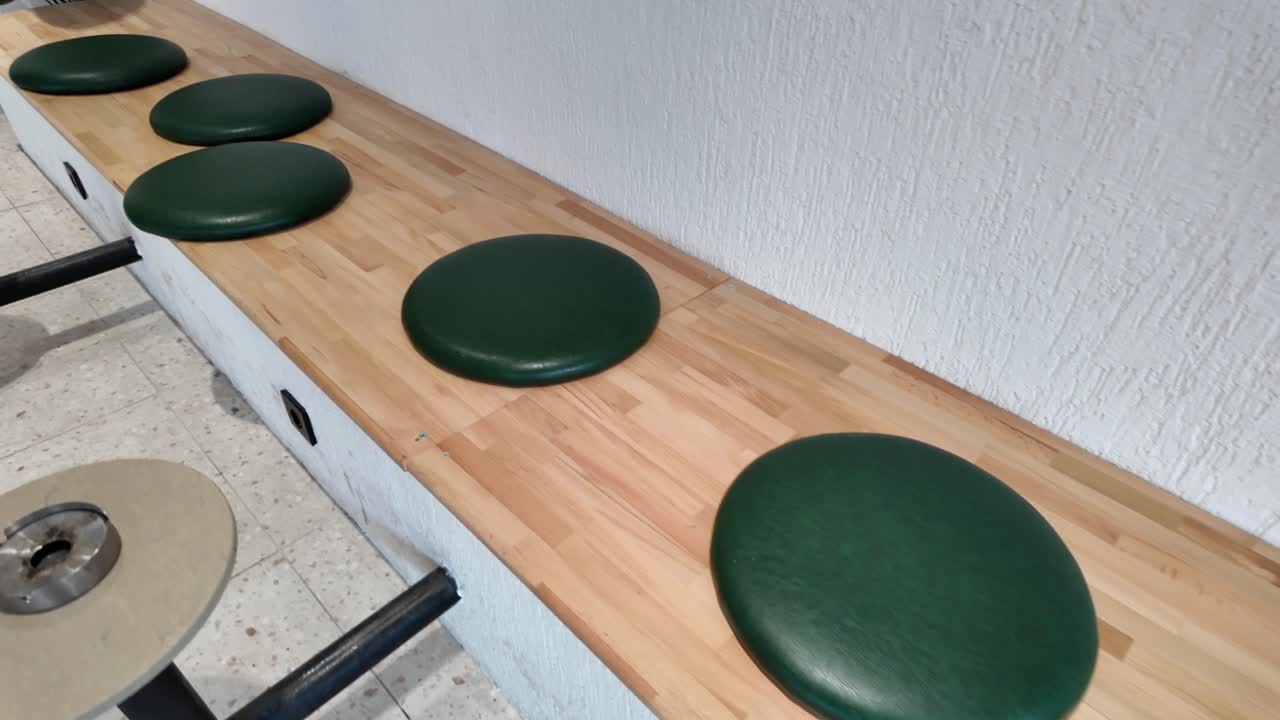 Tom träbänk med gröna dynor i ett modernt kafé.