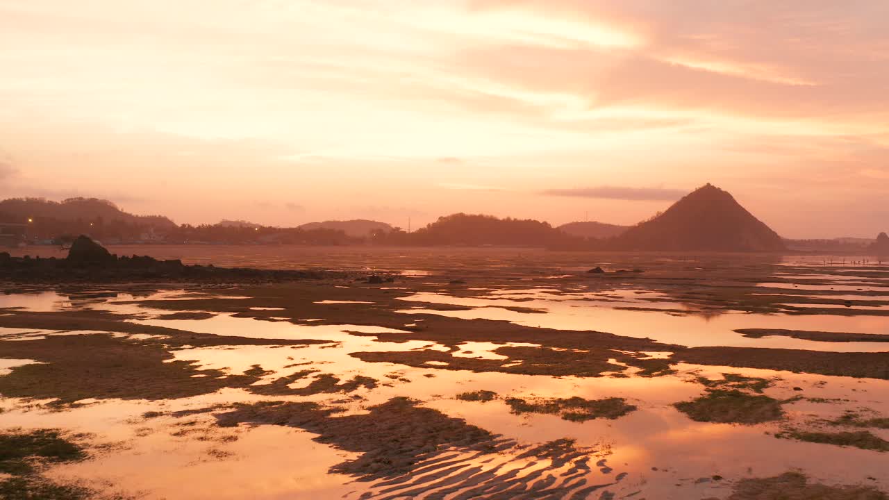 일출 동안 쿠타 롬복의 마른 암초, 현지 사람들이 음식과 조개껍질을 찾고 있습니다.