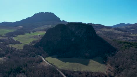 aerial footage of pietra perduca and barcellara, volcanic rocks, church set at top stone immersed in countryside landscape, cultivated land in val trebbia bobbio, emilia romagna, italy