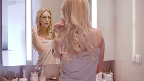 blond woman wrapped in towel in front a mirror