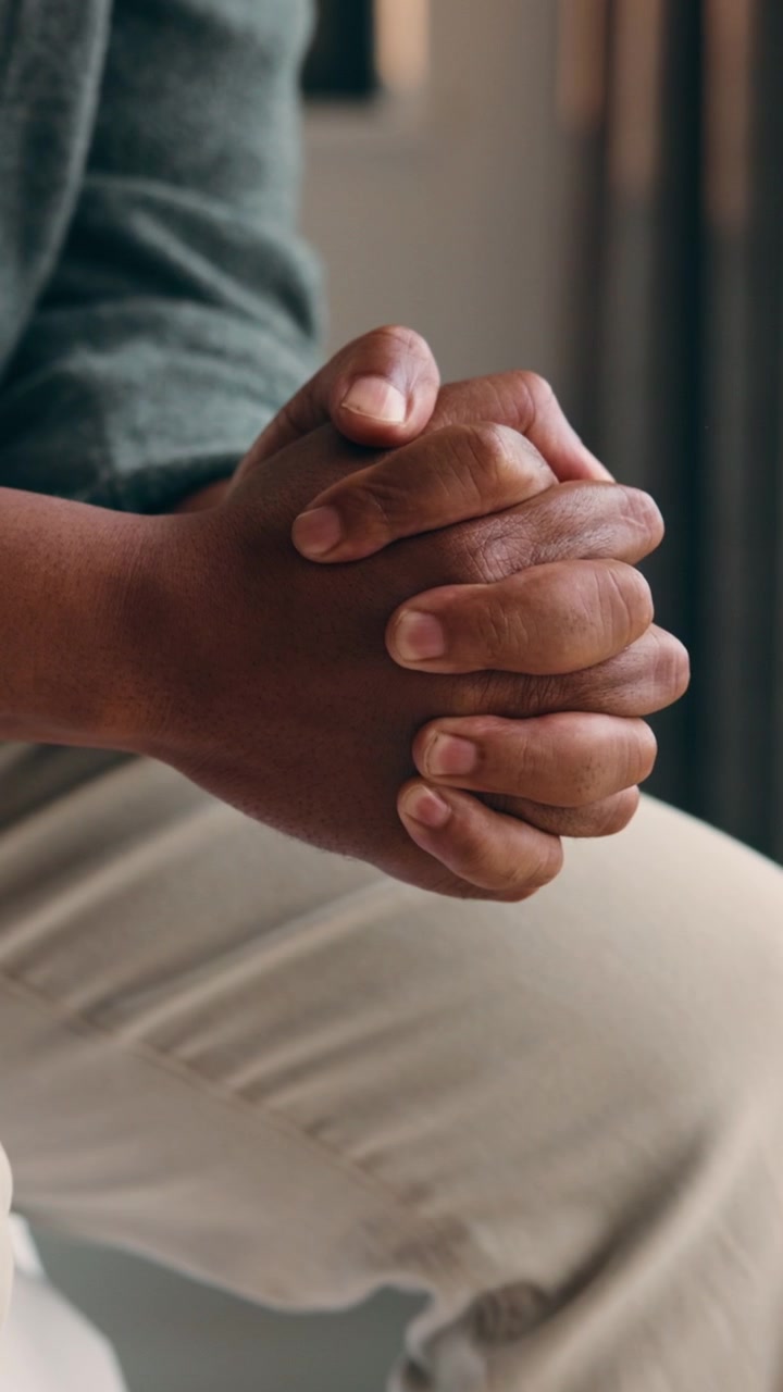 Primo piano di una persona seduta con le mani giunte