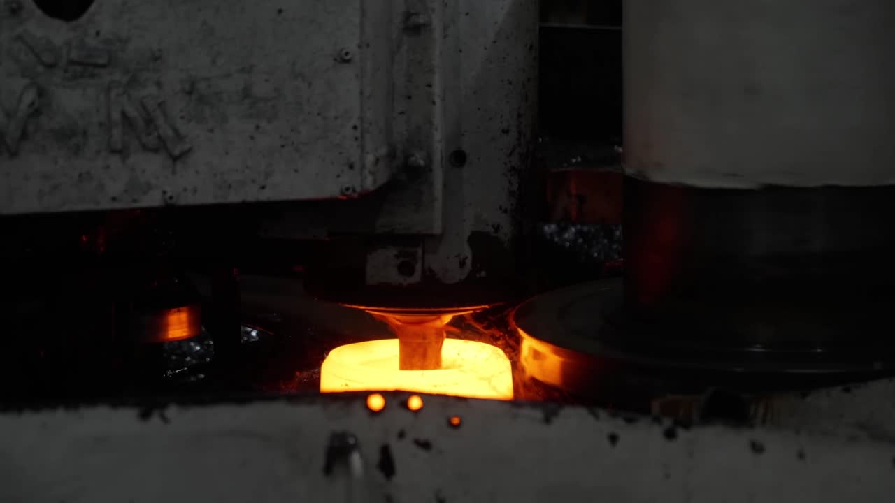 Macchinario industriale automatizzato che modella con precisione un pezzo di metallo incandescente durante un'operazione di forgiatura ad alta velocità