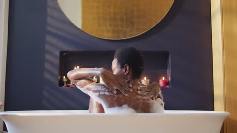 happy african american woman taking bath in bathroom