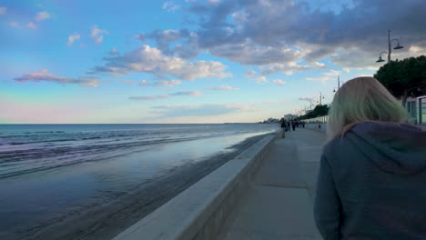 a seaside promenade with people walking along the path by the water in larnaka