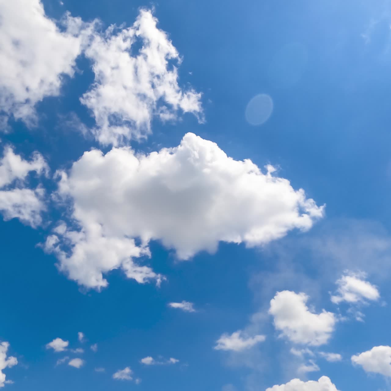 Soft puffy clouds quickly changing shape. Sun rays passing through the cloudscape. Timelapse