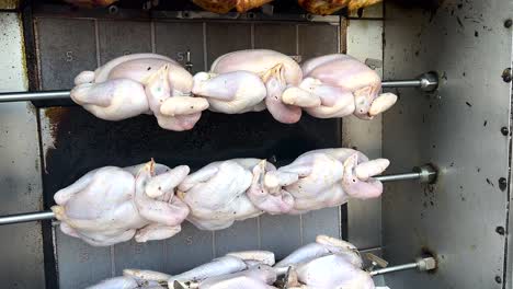 chickens rotating on a grill in nakhon nayok