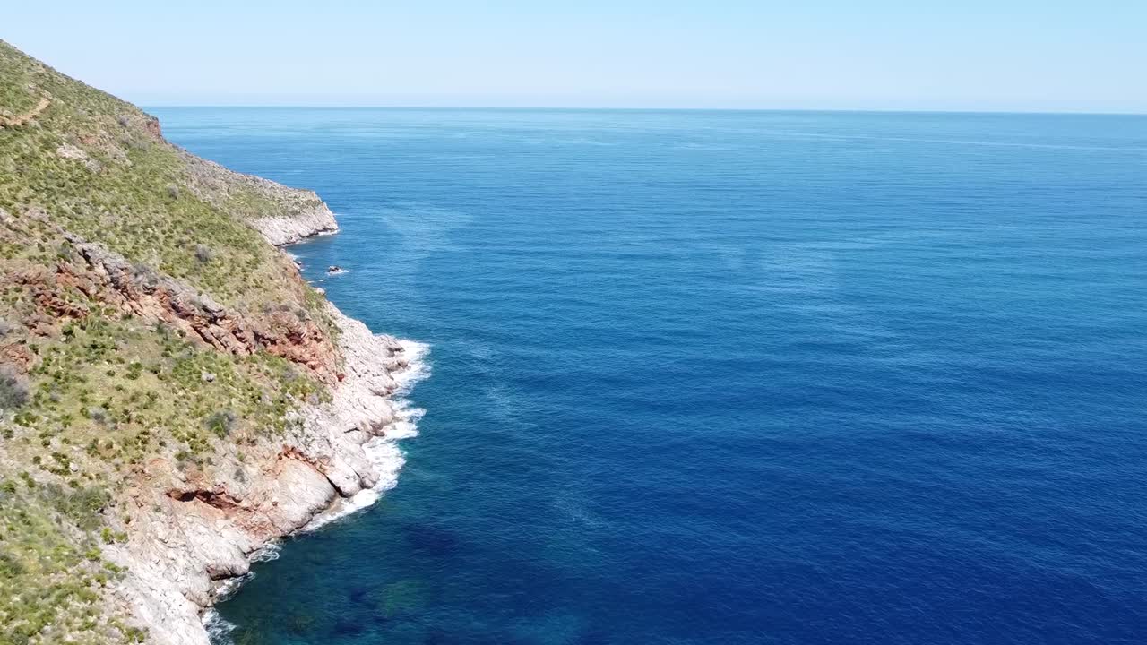 Costa rocciosa con tempo soleggiato, Zingaro sull'isola della Sicilia in Italia (drone vola verso l'orizzonte).