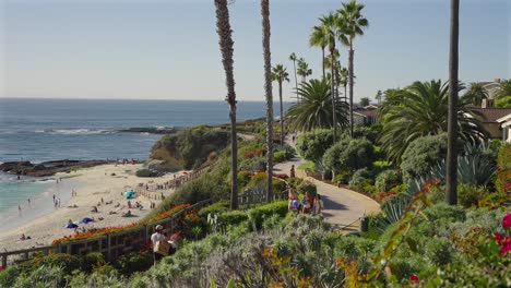 People-walking-along-a-path-above-Treasure-island-Beach,-in-Laguna-Beach,-California