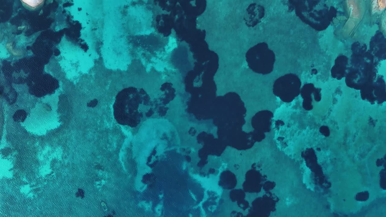 Luftfoto af blåt sardinsk vand med spredte, mørke områder