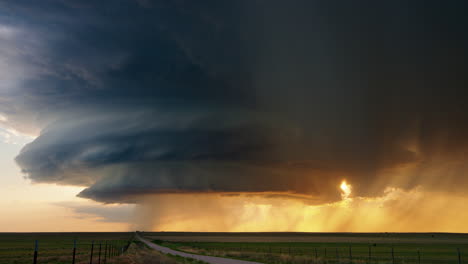 dramatic supercell thunderstorm at sunset over a rural landscape