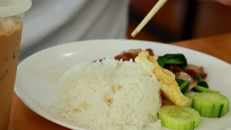 using chopsticks to eat rice, egg, and cucumber