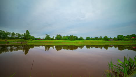 Cinematic-time-lapse-of-clouds-moving-fast-over-a-reflective-lake-with-the-light-changing-throughout-the-day