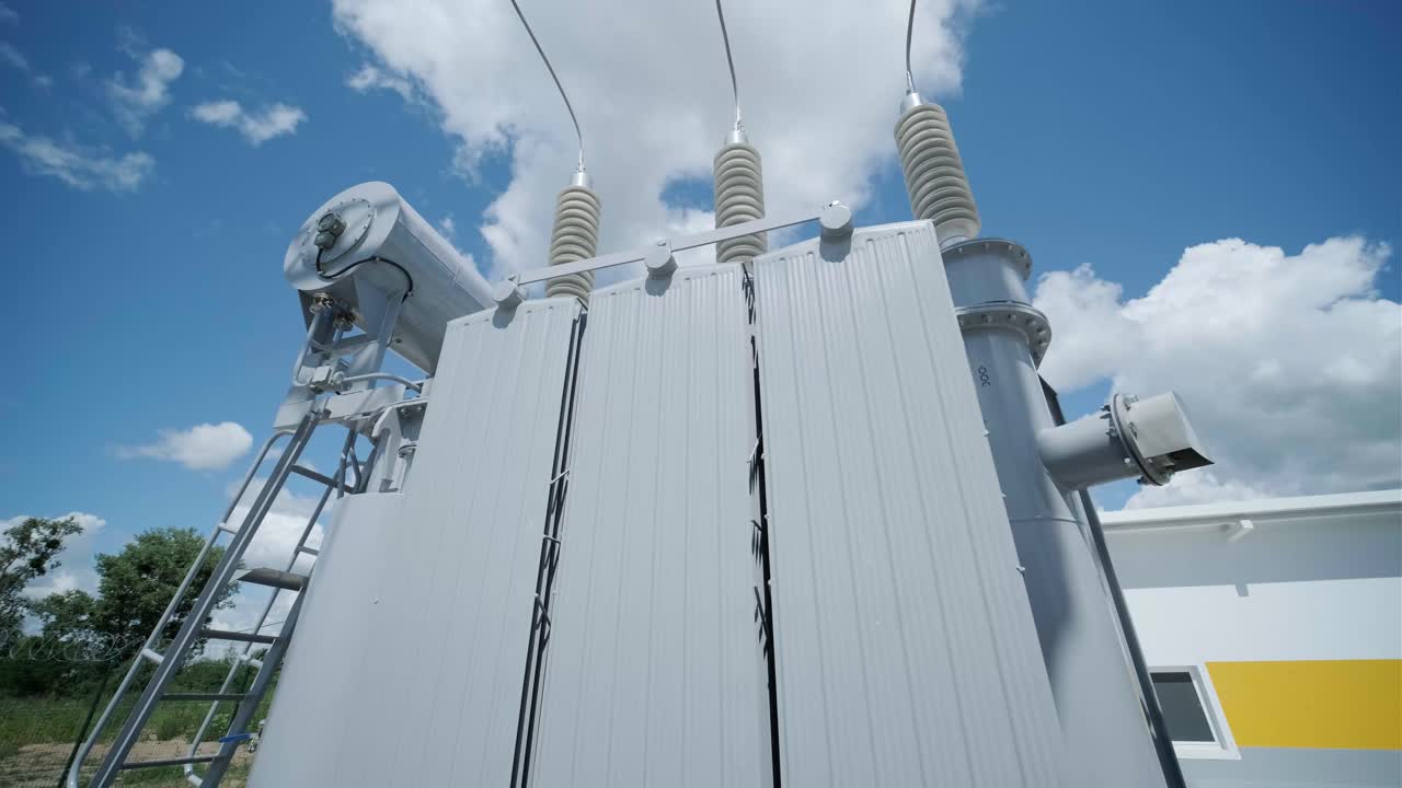 High voltage transformer against the blue sky. Electric current redistribution substation