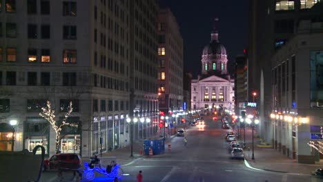 a horse drawn carriage passes the indiana state capital building in indianapolis at night