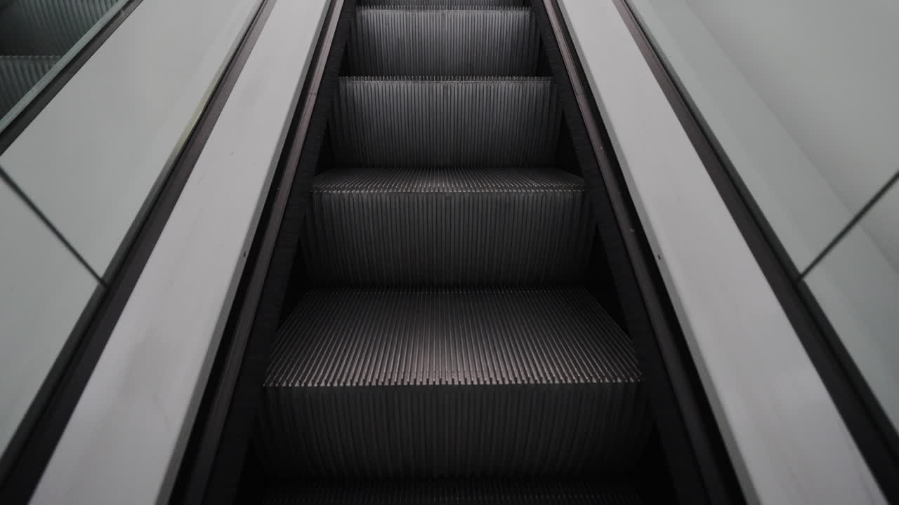 Pov shot riding an empty escalator upwards. Modern automatic stairs moving up to the next floor in a public space like a subway station