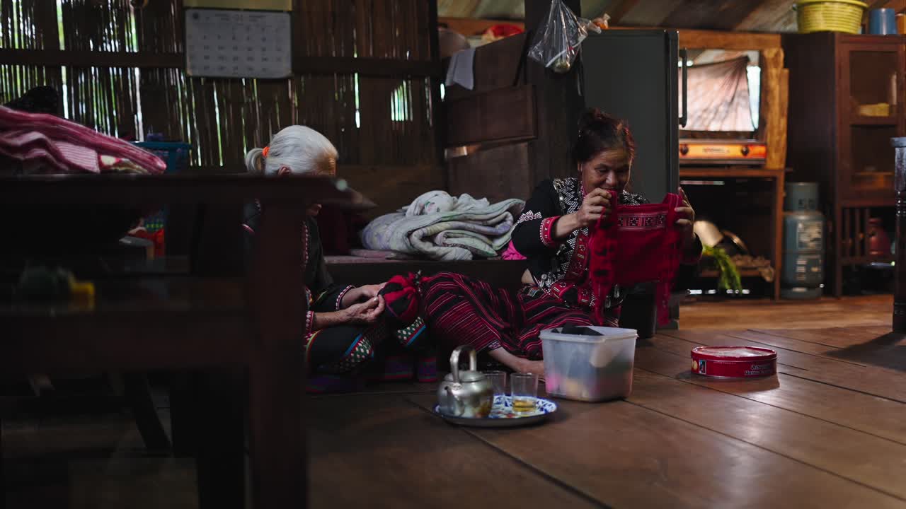 Women in traditional clothing working inside a wooden house