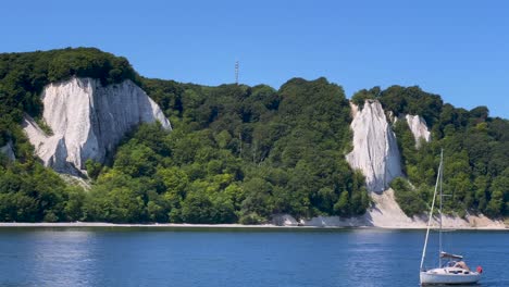 Die-Sehr-Berühmten-Kreidefelsen-Der-Insel-Rügen-In-Deutschland-Mit-Dem-Aussichtspunkt-Königsstuhl,-Von-Der-Ostsee-Aus-Gesehen,-Mit-Einem-Kleinen-Vorbeifahrenden-Segelboot