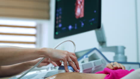 ultrasonic check up for a caucasain woman on early stage of pregnancy. monitor of ultrasound machine at backdrop.
