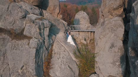 Newlyweds-stand-on-a-high-slope-of-the-mountain.-Groom-and-bride.-Arial-view