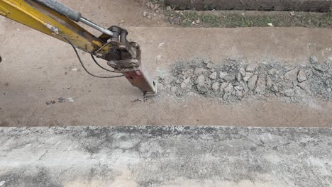 Excavator-breaking-and-drilling-the-concrete-road-for-sewage-line-or-rood-repair