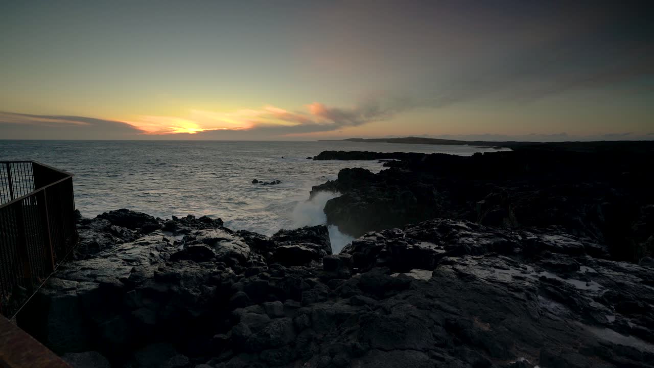 Aallot iskevät kallioiseen rannikkoon auringonlaskun aikaan - laajakuva.