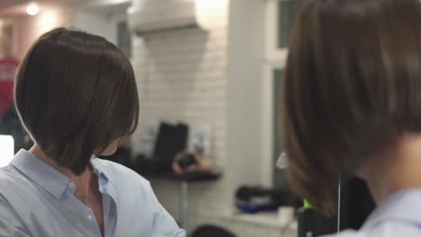 adult woman in shirt looking in the mirror after haircut and touching her hair