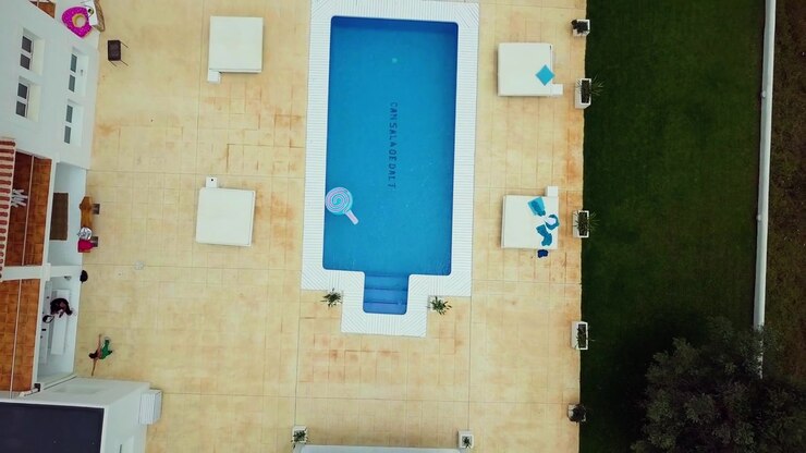 A blue pool sits atop a Venice rooftop as the drone lifts straight up.