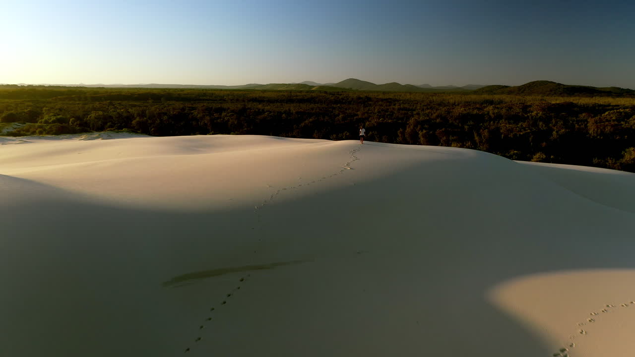 amplia y reveladora toma de drones de un hombre caminando solo en las dunas de arena
