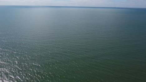 4k aerial view of the pacific ocean with white clouds at the horizon near australia