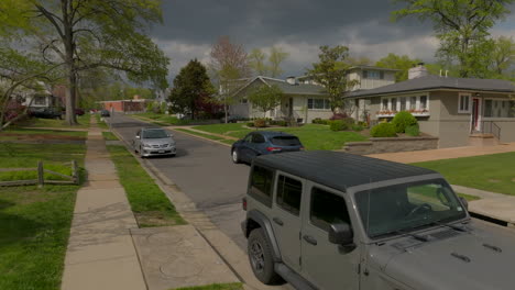 Boom-up-over-nice-residential-neighborhood-as-a-car-drives-past-camera-and-up-the-street-on-a-pretty-spring-day-in-St