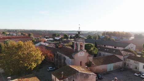 Aerial-view-over-medieval-french-suburb-town-of-Candillargues-in-southern-France,-birds-flying-around-in-group