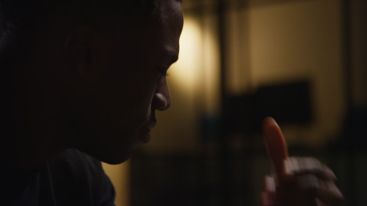 불행하고 우울한 젊은이가 밤에 집에서 소파에 앉아 눈을 감고 머리를 손에 고 있습니다.