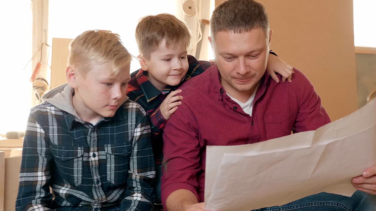 Far og sønner ser på husplaner
