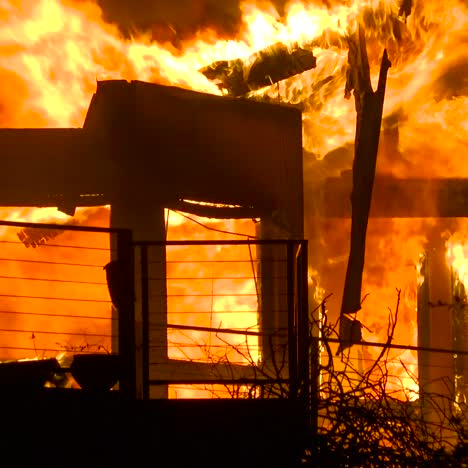 close up of a home burning in a large inferno at night