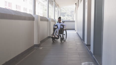 navigating school hallway, african american girl in wheelchair moving independently, focusing ahead