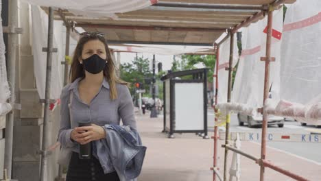 Woman-anxiously-walks-in-big-city-grips-her-bag-little-extra-tight,-face-mask