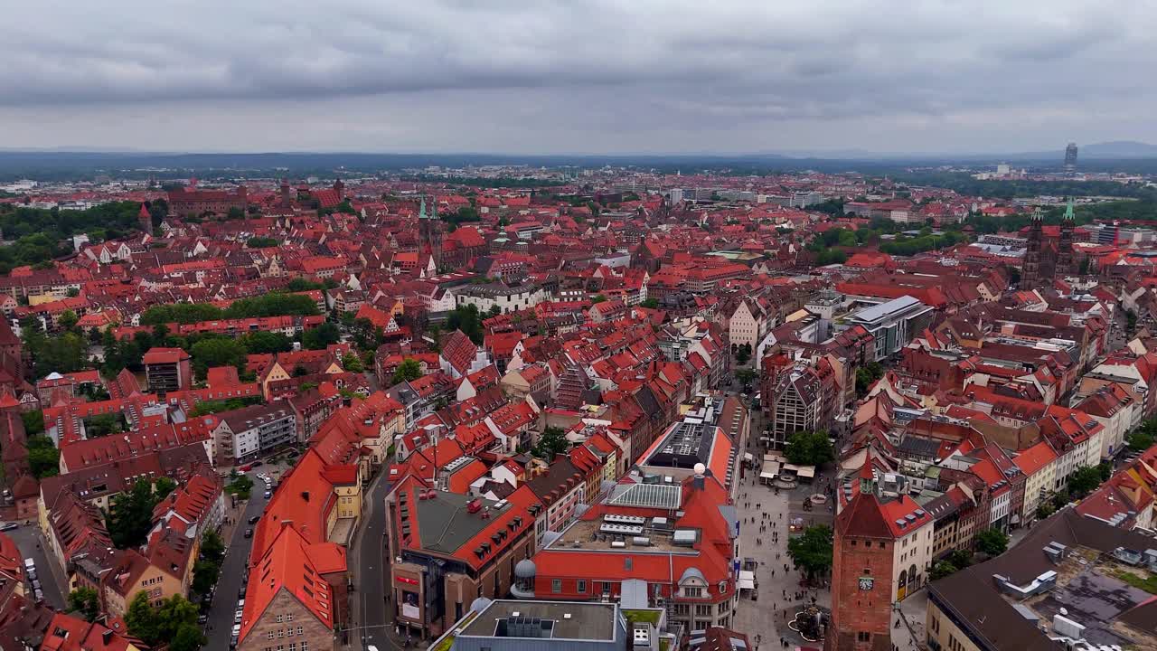 Vista drone sulla Città Vecchia di Norimberga in Baviera, Germania, con tetti di tegole rosse, chiese storiche, la cupola di Sant'Elisabetta e lo skyline medievale sotto cieli drammaticamente nuvolosi.